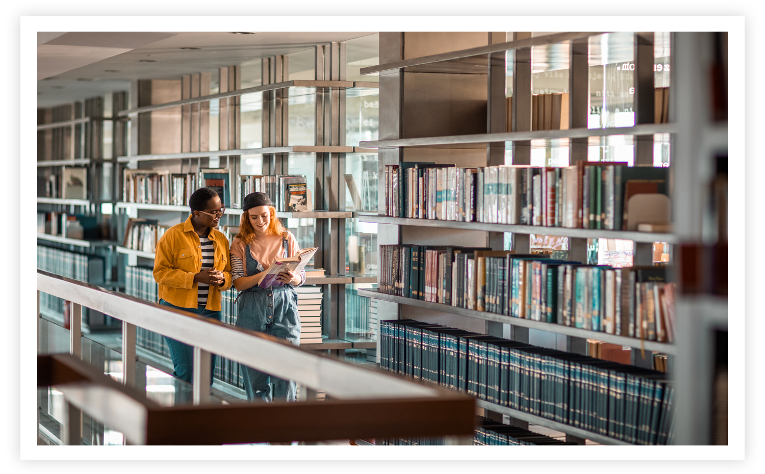 Photo of 2 students walking in library